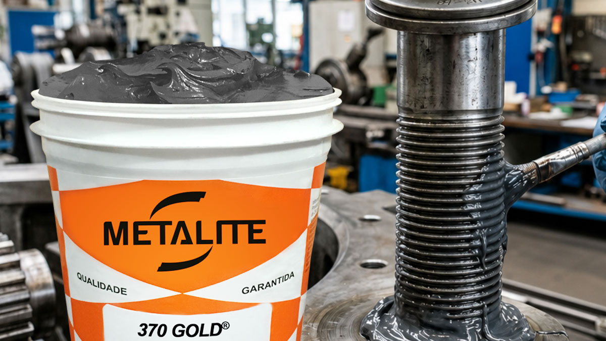 Orange-and-white METALITE bucket filled with dark gray molten material beside a large industrial press in a metalworking shop.